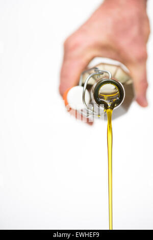 Hand Pouring Extra virgin olive oil from a clear bottle against a white background Stock Photo