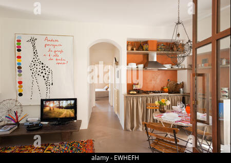 French wire chandelier above café table and chairs in open plan kitchen living space. The giraffe artwork is by Gitte Brandt Stock Photo