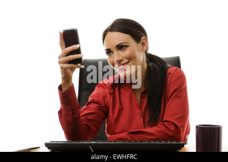 businesswoman sitting at her desk in the office texting someone on her phone Stock Photo