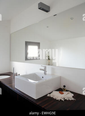 foreground of washbasin in the modern bathroom with wooden top and a large mirror Stock Photo
