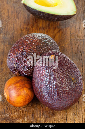 Two ripe avocados and avocado core on an old rustic wooden plank Stock Photo