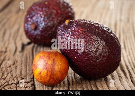 Two ripe avocados and avocado stone on an old rustic wooden plank Stock Photo