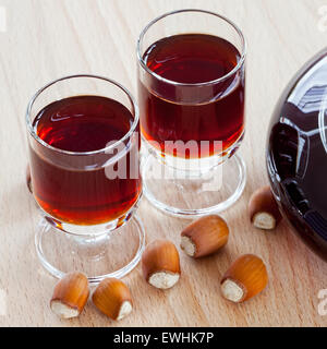 Close up view of homemade hazelnut liqueur in two glasses on wooden background Stock Photo