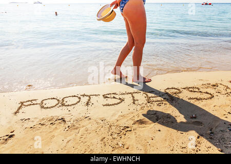 footsteps in sand word written walking on beach coast paddling out in sea coastline Ibiza Spain Spanish Santa Eulalia Del Rio Stock Photo
