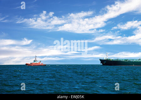 Tug boat towing a tanker ship at sea. Stock Photo