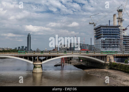 Battersea Park Bridge with a train going over the River Thames and construction work taking place on Battersea Power Station Stock Photo