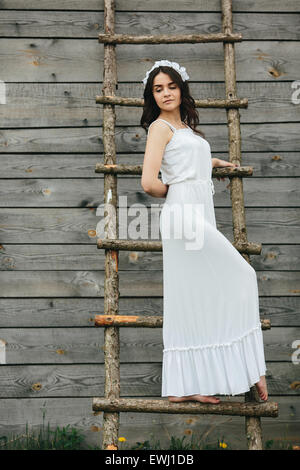 Girl climbing ladder into tree house Stock Photo