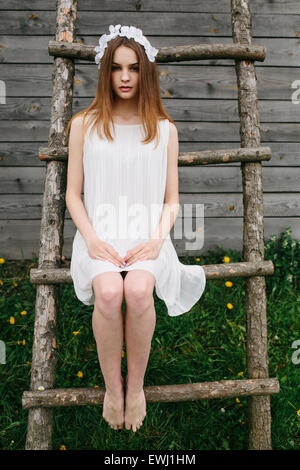 Girl climbing ladder into tree house Stock Photo