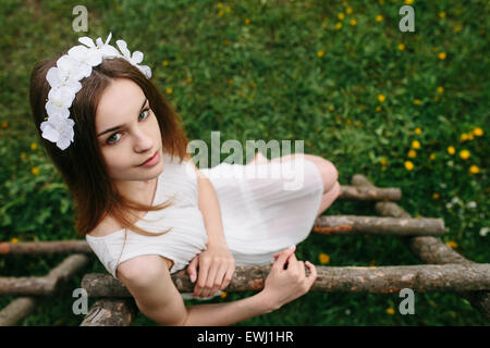 Girl climbing ladder into tree house Stock Photo