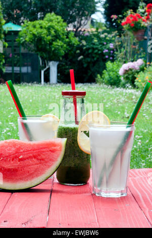 three fresh drinks, a fruit and vegetable smoothie and two lemonades and a piece of watermelon Stock Photo
