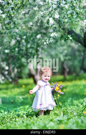 Sweet baby girl playing with beautiful flowers Stock Photo