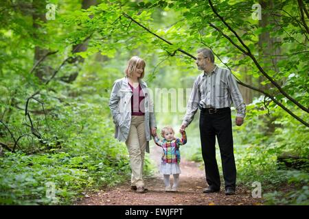Young grandparents playing with their baby granddaughter in an an autumn park Stock Photo