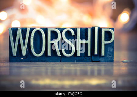 The word WORSHIP written in vintage metal letterpress type on a soft backlit background. Stock Photo