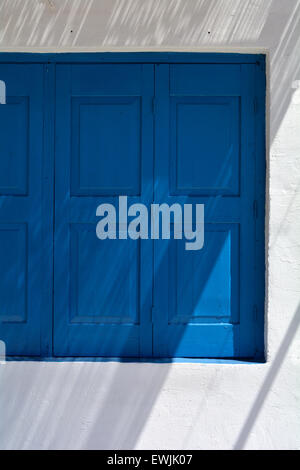 shadows on a white wall and blue shuttered window in the small village of Loutro in Southwest Crete, Greece Stock Photo
