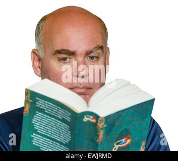 Middle aged Caucasian man reading a paperback book against a white background. Stock Photo