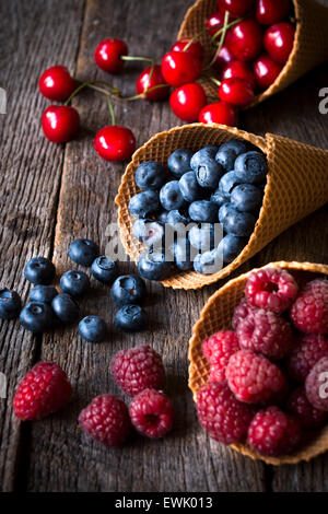 Freshly picked fruits in ice cream cone on wooden background,selective focus Stock Photo