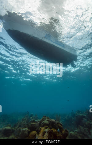 Scuba diving boat floats in clear water above coral reef Stock Photo