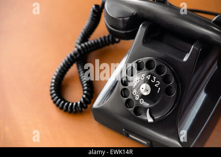 Old fashioned retro rotary dial phone on wooden desk, closeup Stock Photo