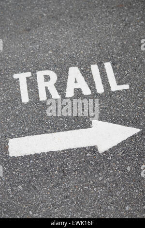 trail sign and arrow painted on gray pavement Stock Photo