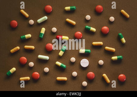 Various pills and tablets on brown textured background. Abstract composition. Stock Photo