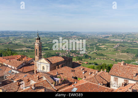 Church among red roofs of small italian town and green hills on background in Piedmont, Northern Italy. Stock Photo