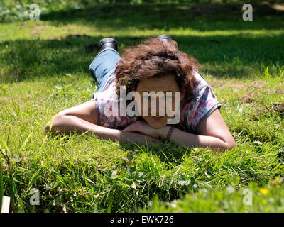 40 year old woman laying on the grass looking at the camera, Somerset, UK Stock Photo