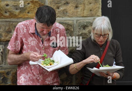 A man and woman eat fish, chips and mushy peas in Bakewell Derbyshire UK Stock Photo