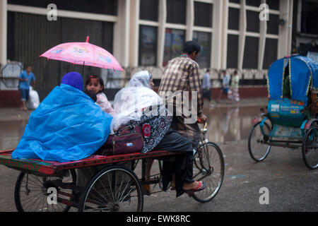 Dhaka, Bangladesh. 27th June, 2015. A family in a van covered with polythene and umbrella during rain  in Dhaka on 27th June 2015.Heavy raining in the city continued for a four consecutive day, inflicting endless suffering on the people as water logging hampered educational and business activities. Credit:  zakir hossain chowdhury zakir/Alamy Live News Stock Photo