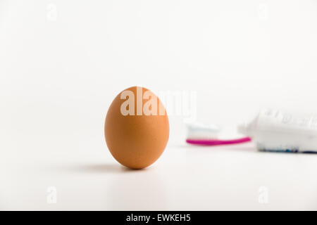egg in the foreground and a toothbrush with paste on a background Stock Photo