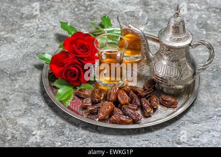 Tea, dates fruits and red rose flowers. Islamic holidays decoration. Ramadan kareem. Eid mubarak. Oriental hospitality concept. Stock Photo