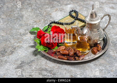 Tea, dates fruits, red rose flower, holy book quran and rosary. Islamic holidays decoration. Ramadan kareem. Eid mubarak. Stock Photo