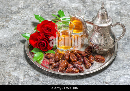 Red rose flowers with tea and dates fruits. Islamic holidays decoration. Ramadan kareem Stock Photo