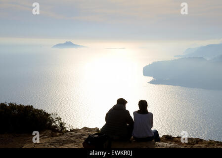 Romantic Young Couple Sitting on Mediterranean Shore Enjoying the Sunset over the Calanques National Park near Cassis Provence Stock Photo