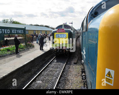 The station porter at Horsted Keynes station on the preserved Bluebell Railway in Sussex hands the Single Line tablet to the crew of visiting preserved Deltic diesel locomotive D9009 'Alycidon' as it passes by another preserved Deltic diesel [preserved Deltic diesel locomotive] on its journey from Sheffield Park to East Grinstead. Stock Photo