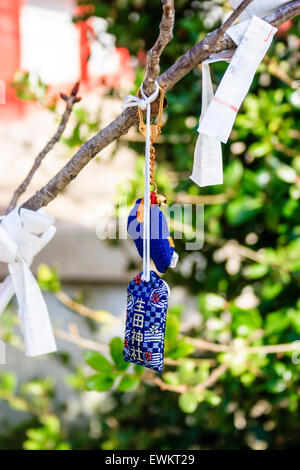 Close up of bad luck Omikuji fortune paper slips tied to twigs and small branches of a tree at the Ikuta Shinto Shrine in Kobe. Stock Photo