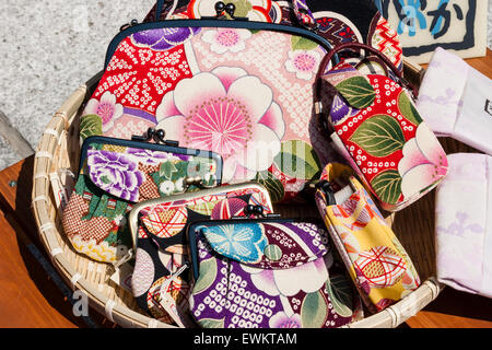 Japan, Kyoto. Straw basket on table outdoors, with colourful woven ladies purses with traditional Japanese patterns being sold as souvenirs. Stock Photo