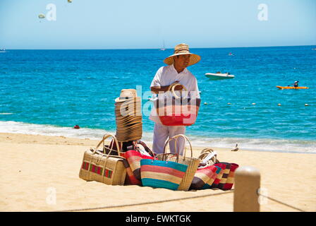 Local Mexican man selling straw bags and hats on beach in Cabo San Lucas, Mexico. Stock Photo