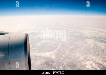 Aerial view from plane of North eastern Russia, Siberia. Mountains covered by snow and ice viewed from 30,000 feet. Engine cowling in  picture. Stock Photo