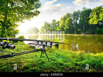 Fishing rods near calm river in the morning Stock Photo