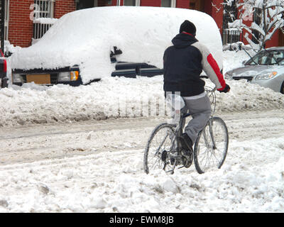 Cyclist riding bike in deep snow on road Stock Photo
