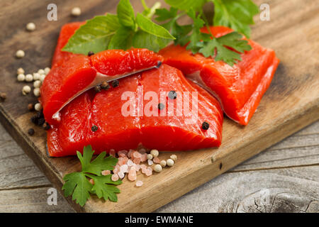 Top view shot of fresh bright red Copper River salmon fillets on cutting board, sea salt and herbs. Stock Photo
