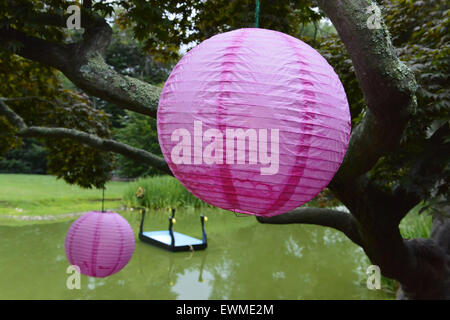 June 28, 2015 - Old Westbury, New York, United States - Colorful pink round lanterns, hanging from trees around the pond, decorate the grounds of historic Old Westbury Gardens, a Long Island Gold Coast estate, during its Midsummer Night event. (Credit Image: © Ann Parry/ZUMA Wire) Stock Photo