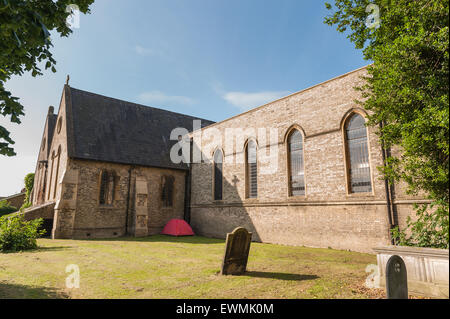 homeless no where to live so put up in red tent in churchyard charitable act helping left alone in Chelmsford city Stock Photo