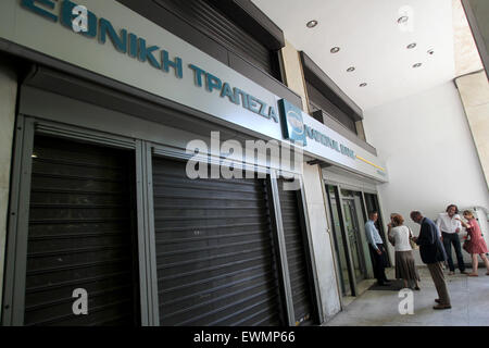 Athens, Greece. 29th June, 2015. Greeks gather in front of a closed bank in central Athens, Greece, June 29, 2015. Greek banks will stay closed before July 6, one day after a planned referendum on bailout proposals, and ATM withdrawals will be limited to 60 euros (65 U.S. dollars) a day per bank card in the same period, the government said early Monday. Credit:  Marios Lolos/Xinhua/Alamy Live News Stock Photo