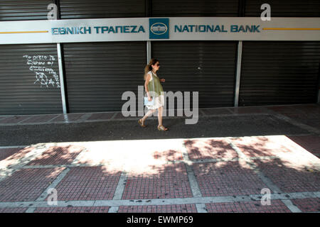 Athens, Greece. 29th June, 2015. A woman walks past a closed bank in central Athens, Greece, June 29, 2015. Greek banks will stay closed before July 6, one day after a planned referendum on bailout proposals, and ATM withdrawals will be limited to 60 euros (65 U.S. dollars) a day per bank card in the same period, the government said early Monday. Credit:  Marios Lolos/Xinhua/Alamy Live News Stock Photo