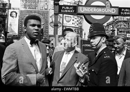 Cassius Clay aka (Muhammad Ali left) with Dave Edgar, Jack Solomon's representative who is looking after him in London, takes a look round the Piccadilly Circus area...and a Policeman asks them to move on. 26th May 1963 Stock Photo