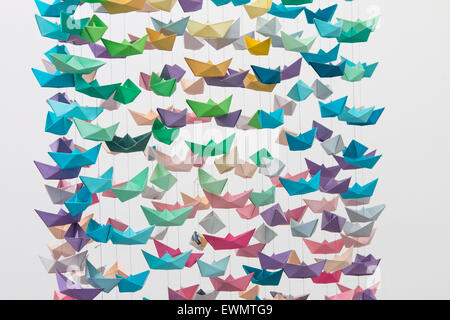 Many colorful paper boats laced together, hanging from the ceiling.