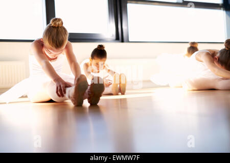 Little Ballet Girls Doing a Sit and Reach Warm-up Exercise for Body Stretching Inside the Studio, Prior to their Dance Rehearsal Stock Photo
