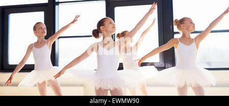Young ballerinas practicing a choreographed dance all raining their arms in graceful unison during practice at a ballet school Stock Photo
