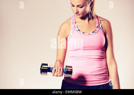 Young woman standing working out upper body, doing a bicep curl. Stock Photo